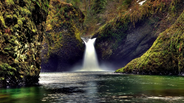 Waterfall cascading into a pool surrounded by mossy rocks