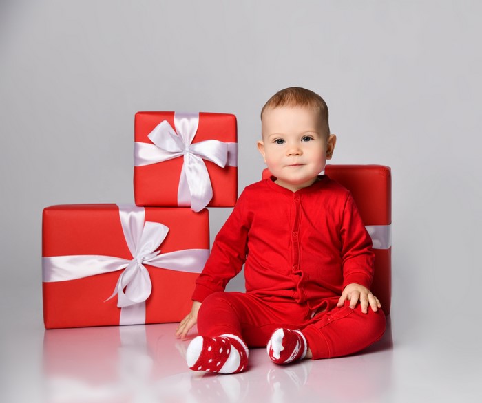 Baby in red pajamas with Christmas gifts