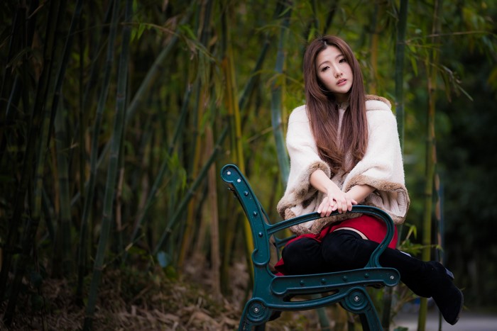 Asian woman with brown hair sitting on a bench