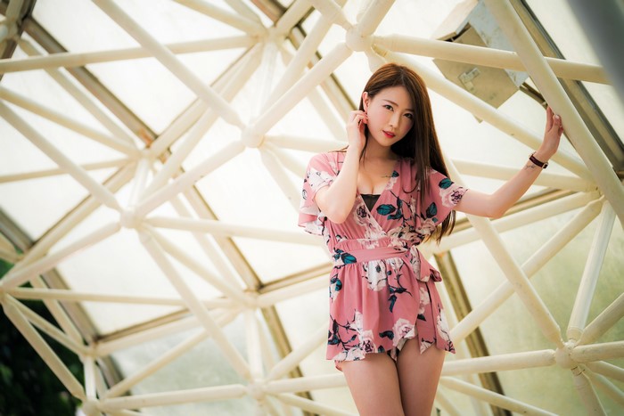 Asian woman in floral dress posing near geometric structure