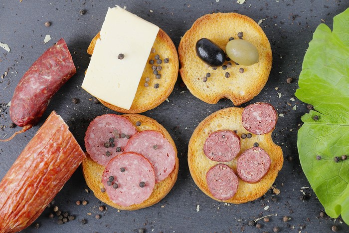 Sausage and cheese on bread with olives and pepper