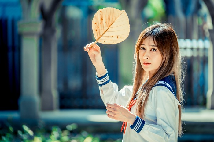 Asian girl in school uniform holding a leaf