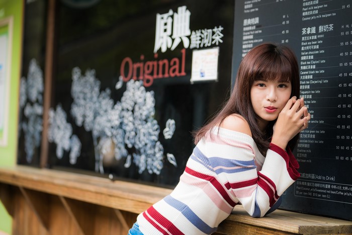 Asian woman in sweater posing near menu