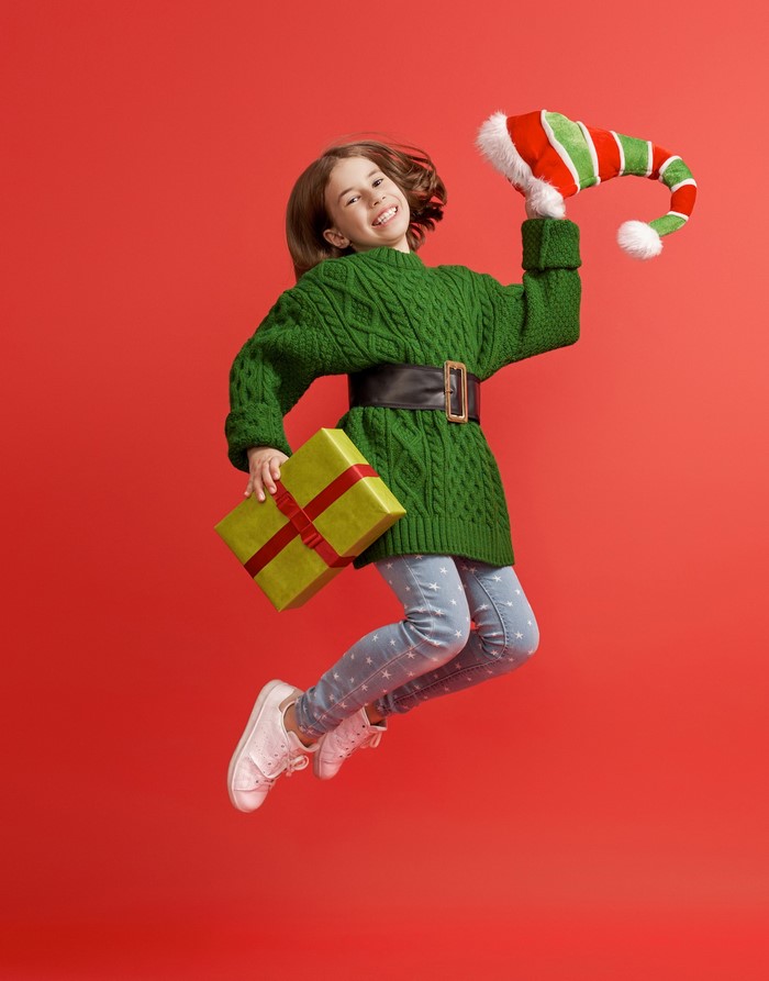 Girl in Elf Costume Jumping with Christmas Gift