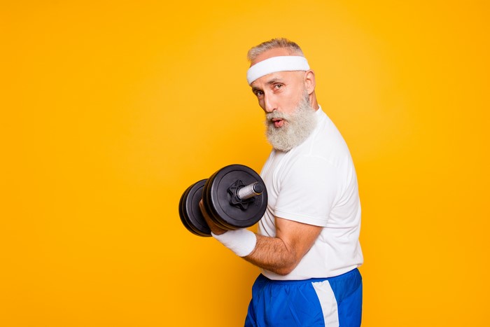 Old man with beard lifting dumbbells