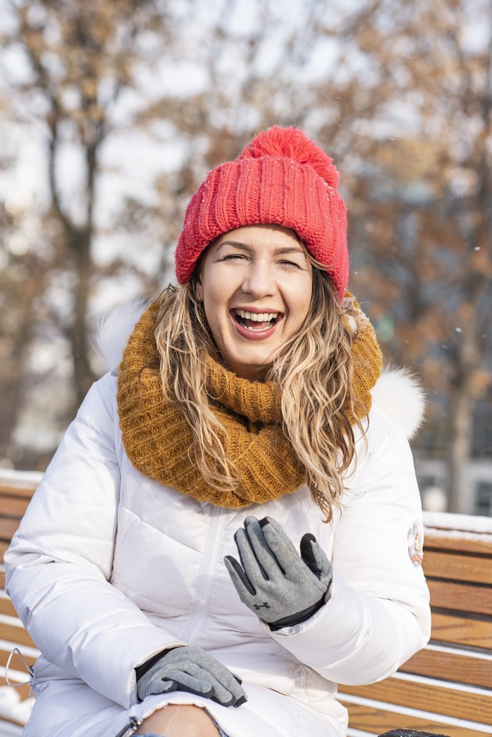 Woman in winter clothes laughing outdoors