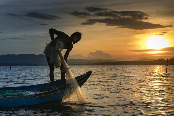 Fisherman casting net at sunset