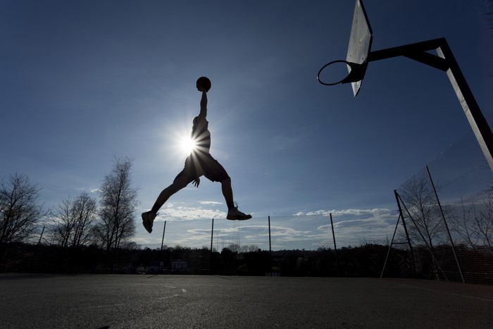 Silhouette of a man dunking a basketball