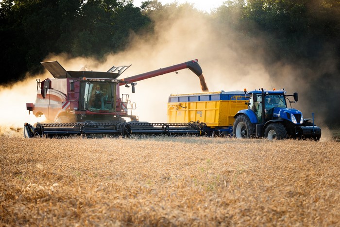 Combine harvester and tractor harvesting a field