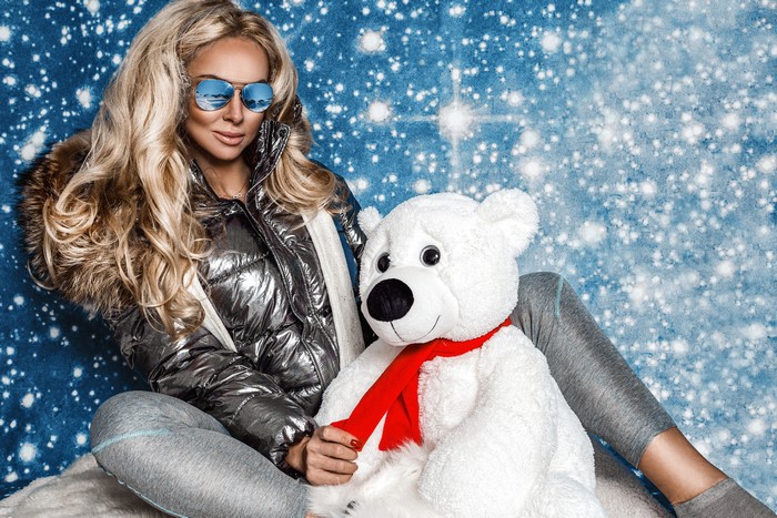 Blonde woman with teddy bear in snowy background
