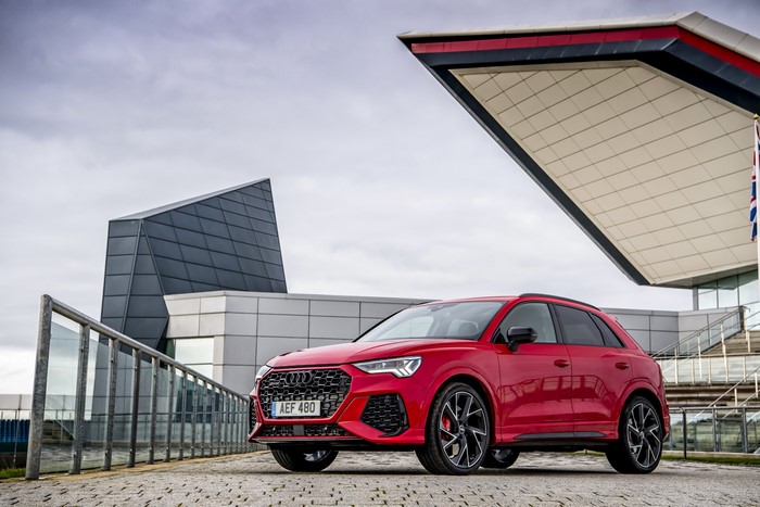 Red Audi RS Q3 parked near modern architecture