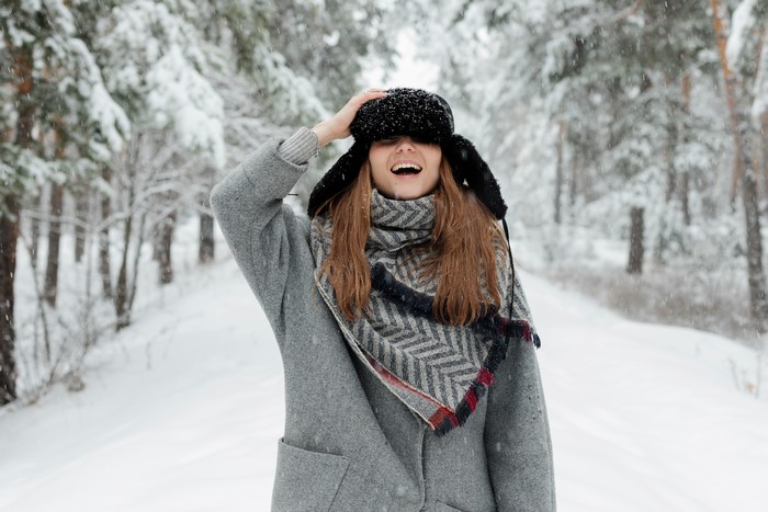 Woman in winter hat and coat in snowy forest