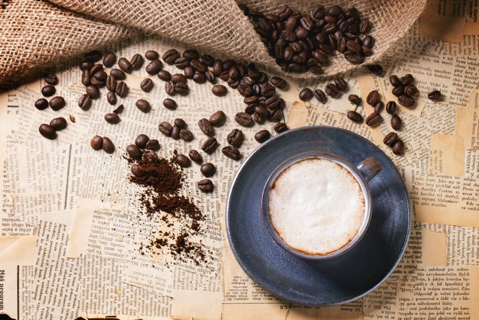 Coffee beans and cappuccino on old newspapers
