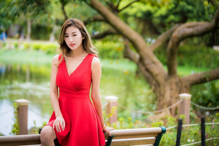 Asian woman in red dress by lake