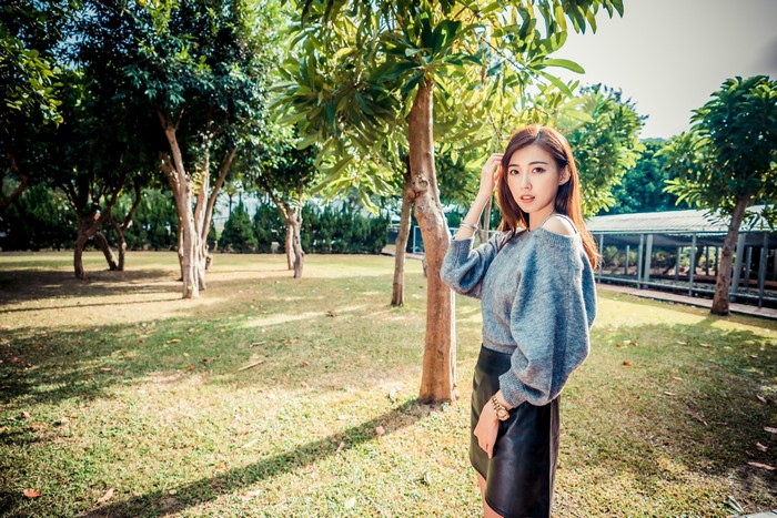 Asian woman with brown hair posing in a park
