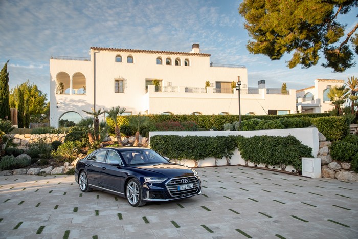 Blue Audi S8 parked in front of a white villa