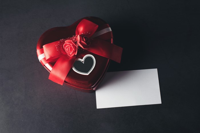 Red heart-shaped gift box with roses and a blank card