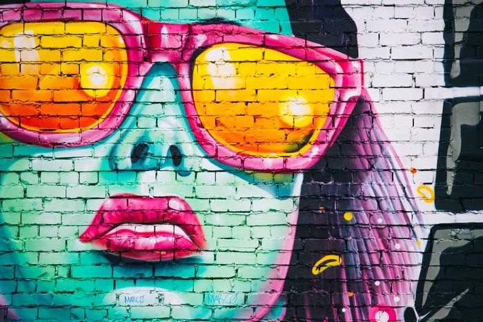 Graffiti of a woman's face with sunglasses on a brick wall