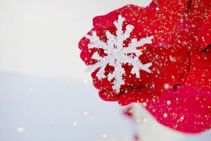 Hands in red gloves holding a snowflake