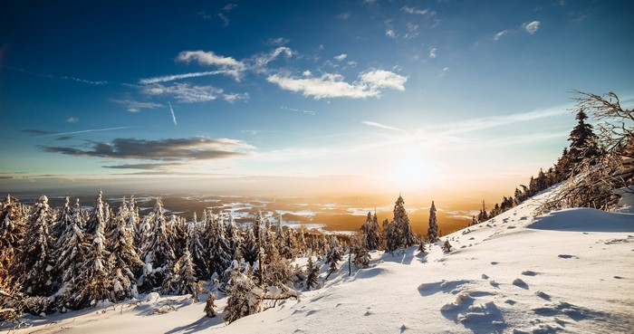 Winter mountain scenery with snow-covered trees and sunset