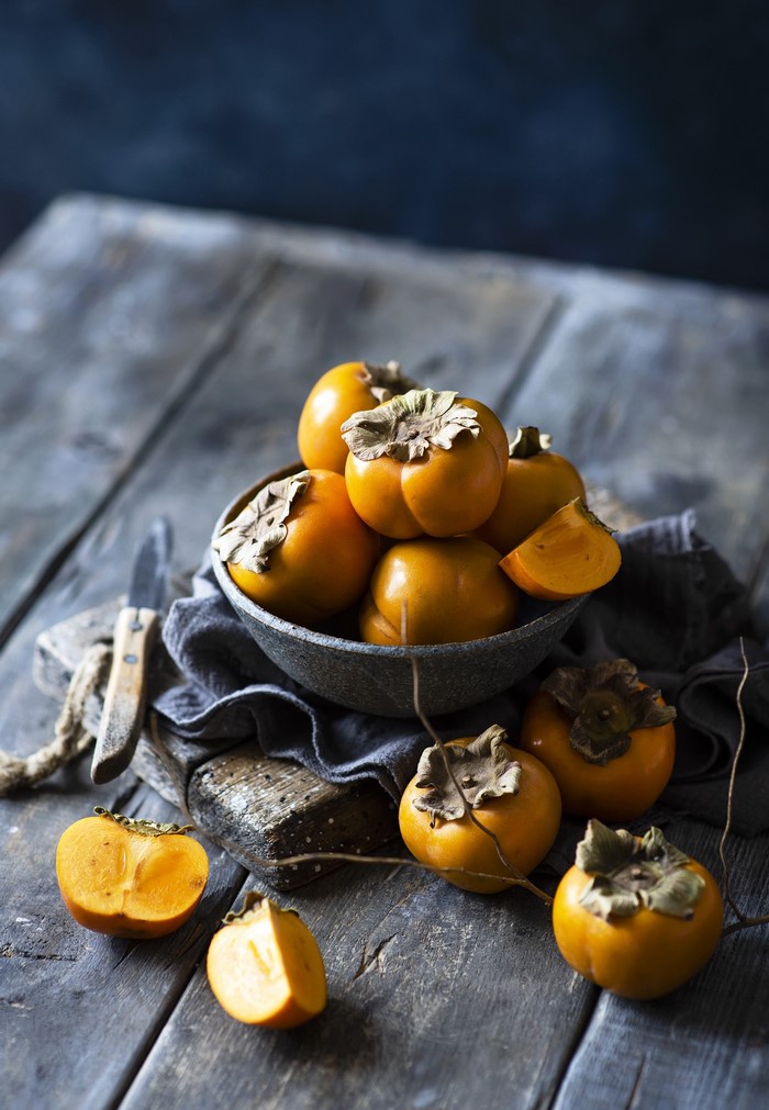 Persimmons in a bowl on a wooden table