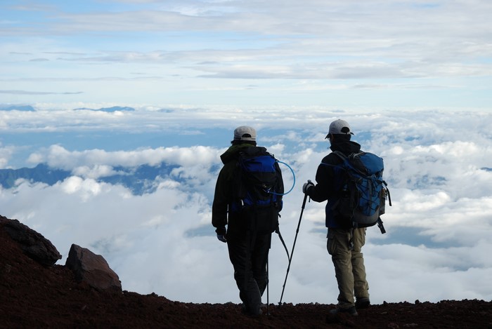 Two climbers with backpacks above the clouds