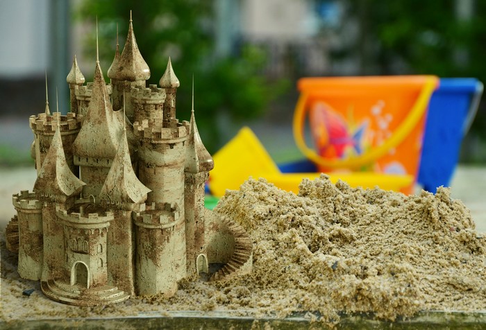 Sandcastle with toy buckets in the background