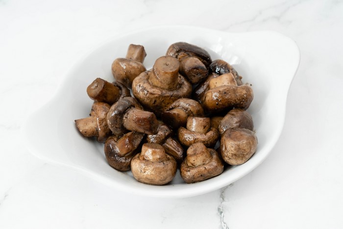 Cooked whole button mushrooms in a white bowl