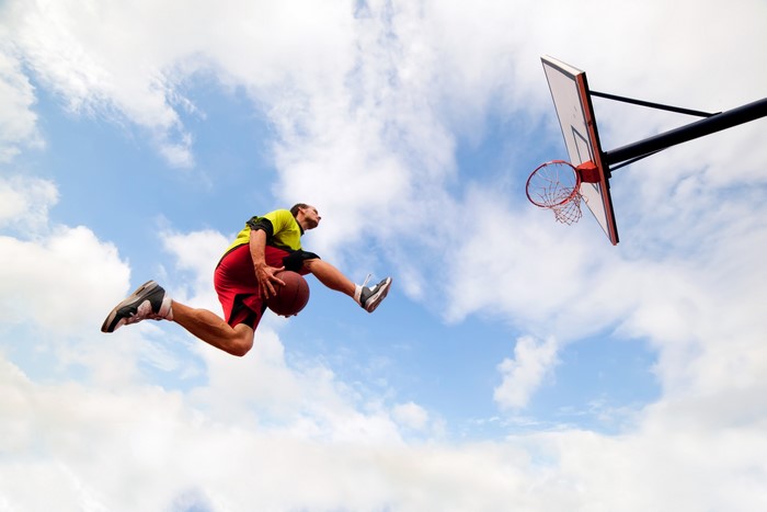 Basketball player dunking against the sky