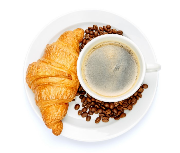 Croissant and coffee with coffee beans on a plate