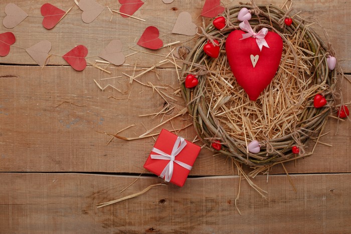 Valentine's Day wreath with hearts and gift on wood