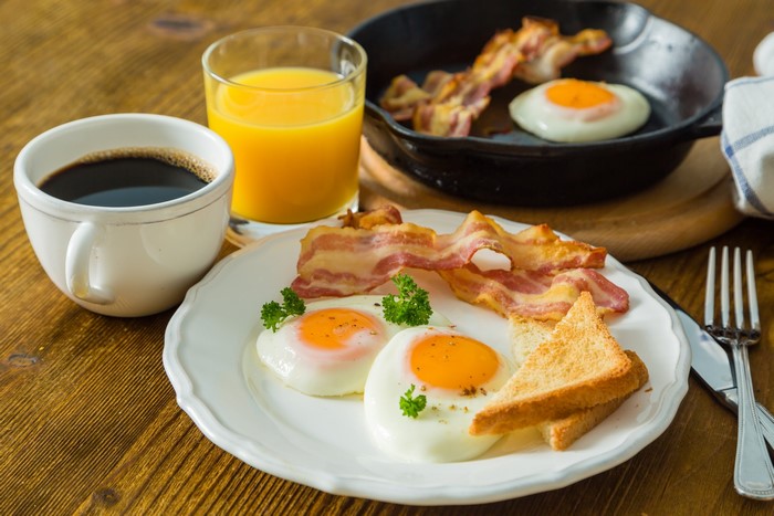 Fried eggs, bacon, toast, coffee, and orange juice