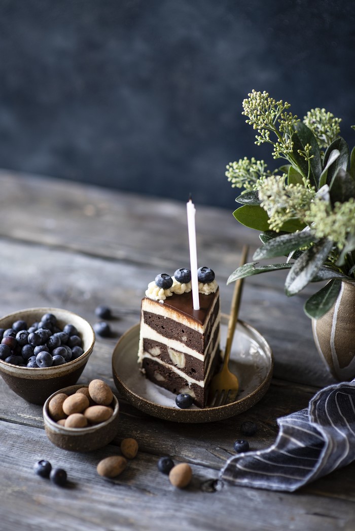 Slice of chocolate cake with blueberries and candle