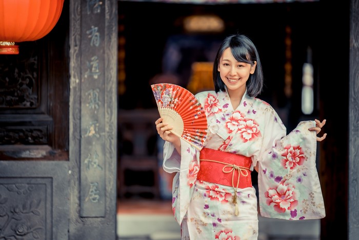 Brunette girl in kimono holding a fan
