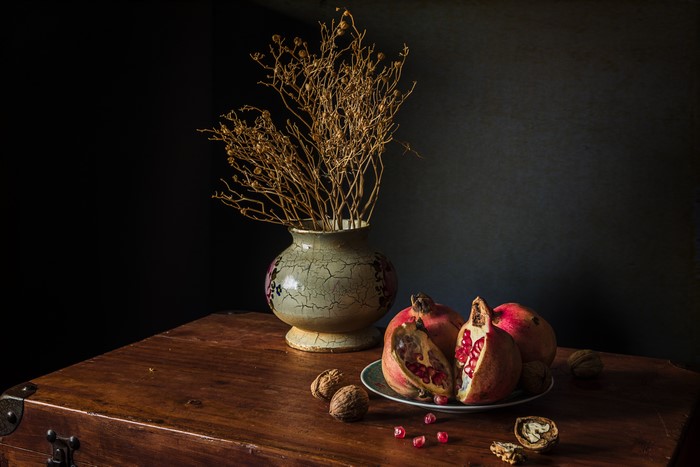 Still-life with pomegranates, walnuts, and a vase of dried flowers