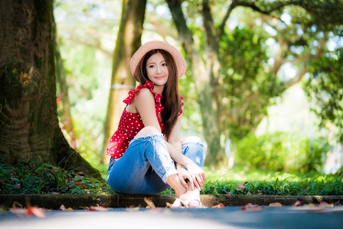 Asian woman in red polka dot blouse and jeans wearing hat