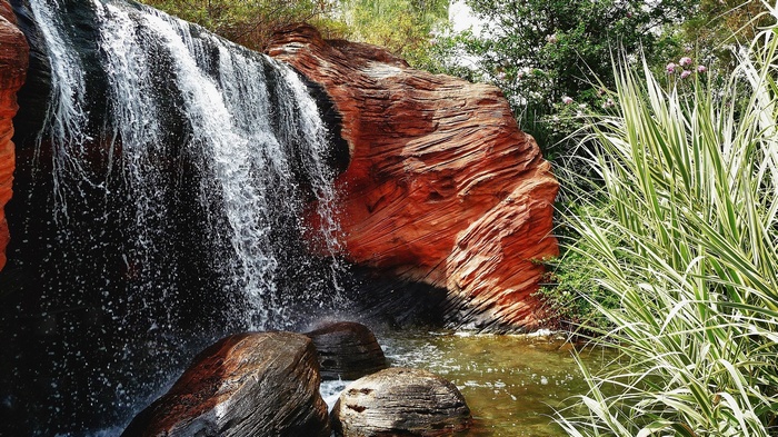 Waterfall cascading over red rocks with plants