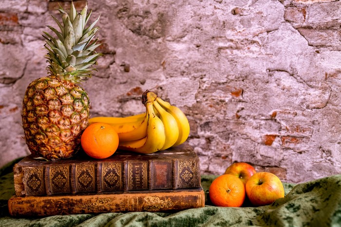 Still-life with pineapple, bananas, oranges, apples, and books