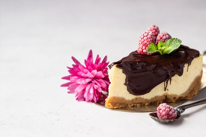 Slice of chocolate cheesecake with raspberries and flower