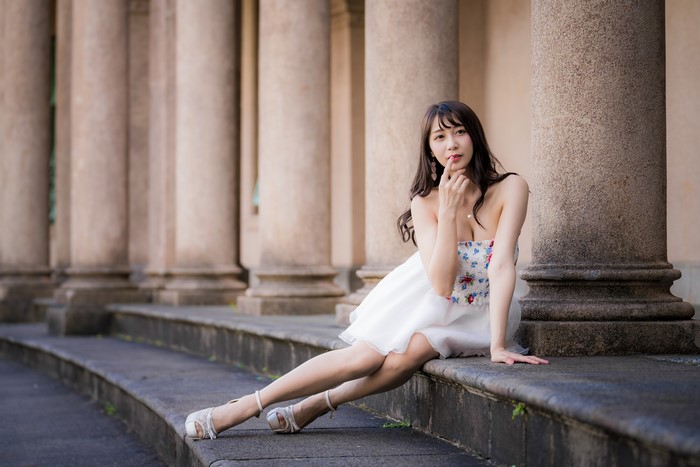 Asian woman in white dress sitting by columns