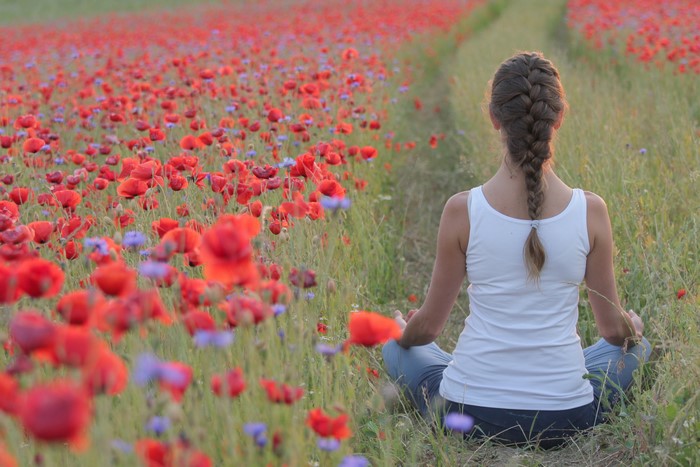 Woman meditating in a field of poppies