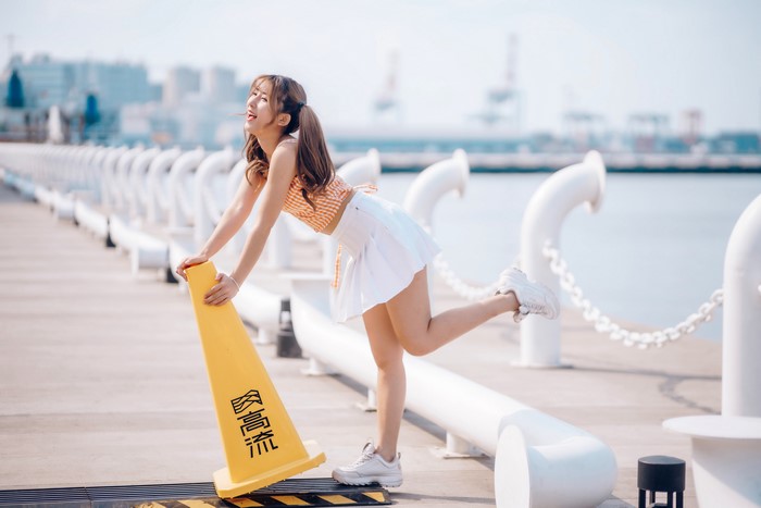 Asian Woman Posing with Traffic Cone on Waterfront