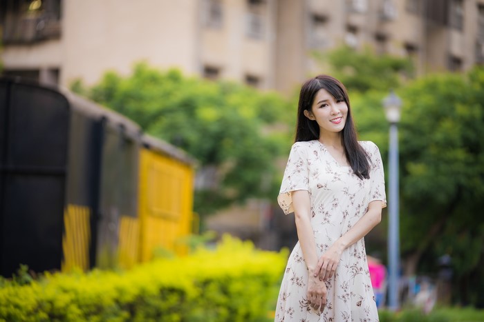 Asian woman in floral dress with train in background
