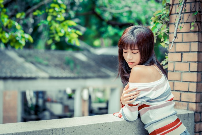 Asian woman with brown hair wearing a striped off-the-shoulder top