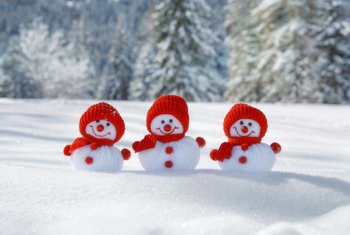 Three snowmen with red hats and scarves in the snow