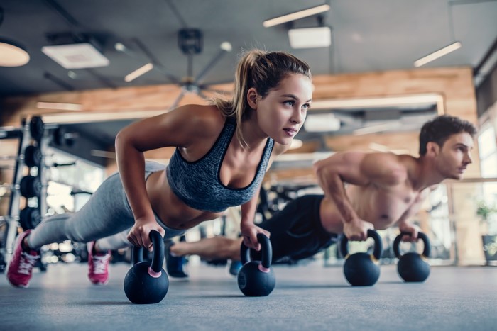 Man and woman doing push-ups with kettlebells