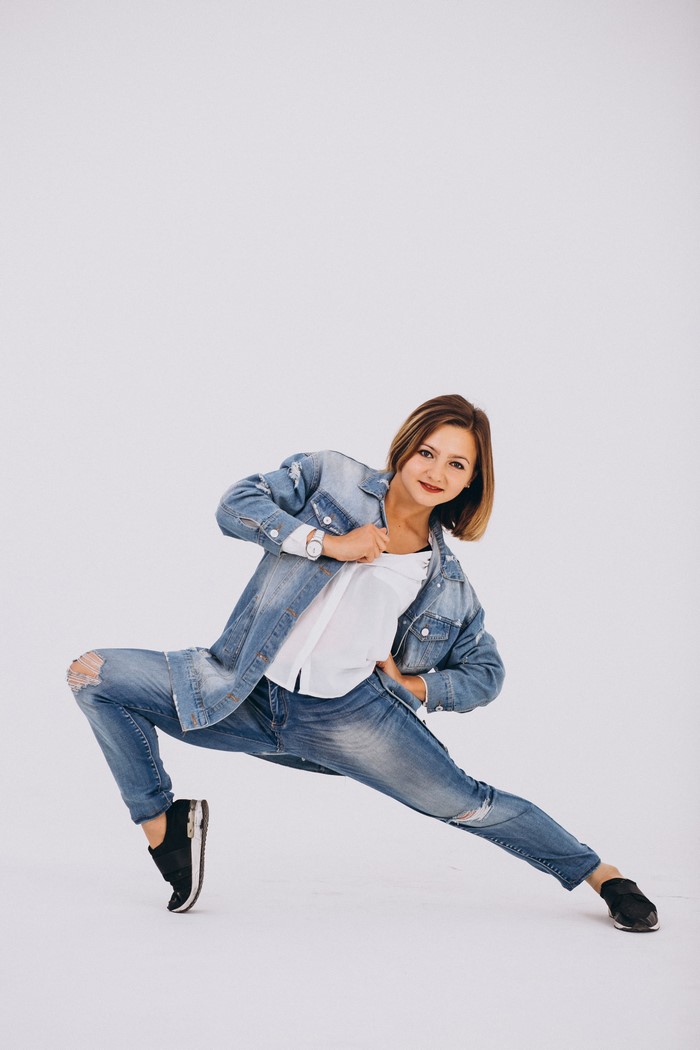 Woman in denim outfit dancing on gray background