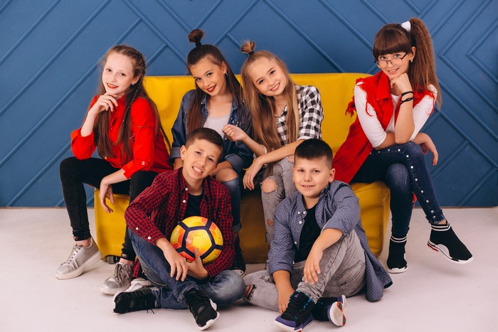Children posing with a soccer ball on a yellow couch