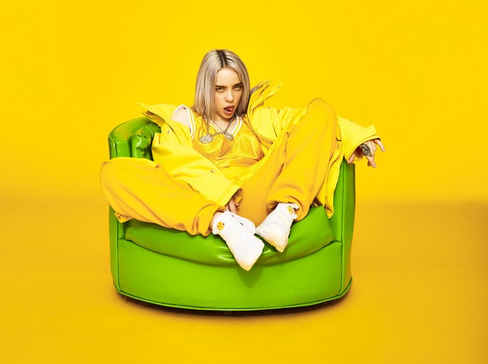 Billie Eilish Sitting on Green Armchair in Yellow Outfit