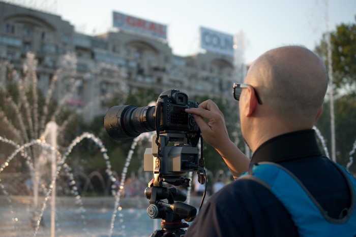 Photographer with camera and tripod near fountains